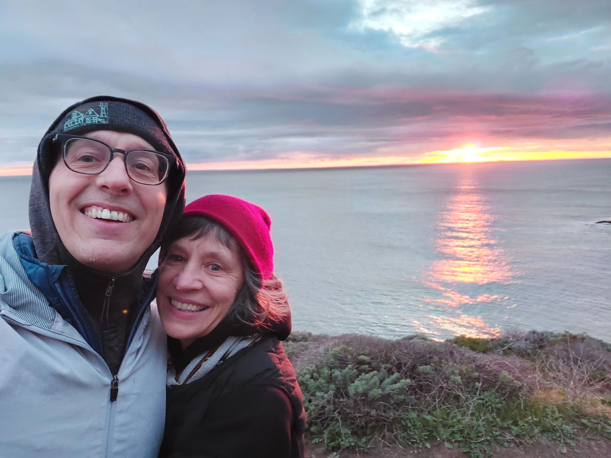 Ed Frauenheim and Rowena Richie smile at the camera in front of a body of water.