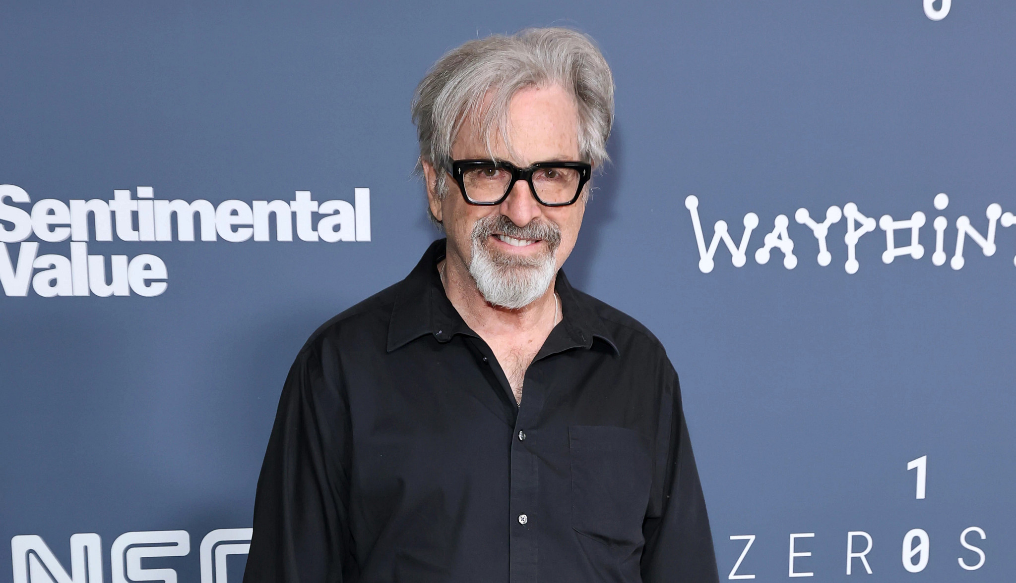 robert carradine standing in front of a blue background