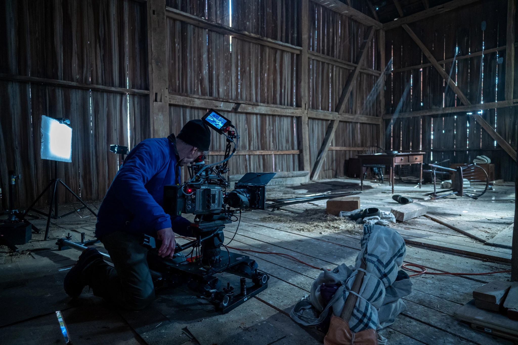 a cinematographer filming inside of an old barn
