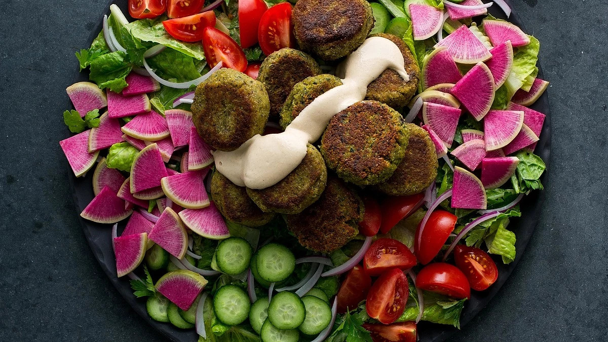 A close-up view of falafel salad with lemon-tahini dressing on a plate