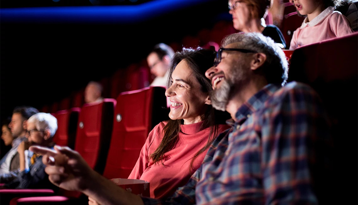 Movie Tickets Couple enjoying movie in the theater with red seats