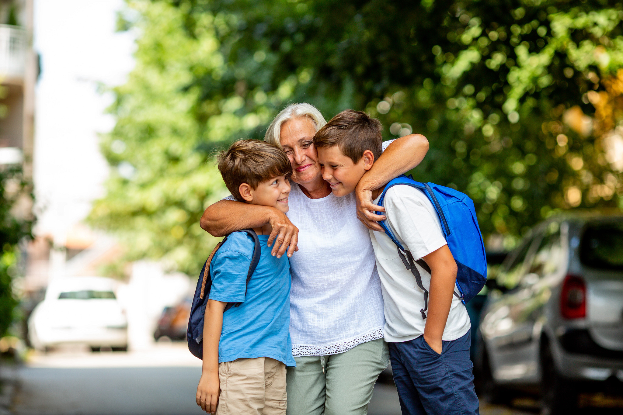 a mom hugging her kids with backpacks on 
