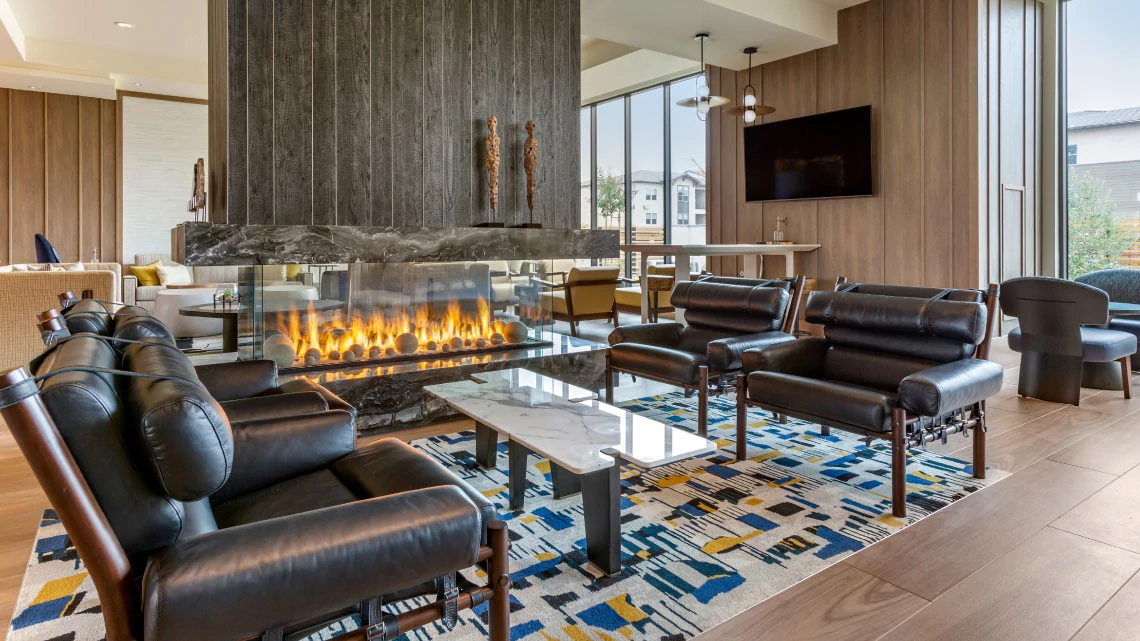 Cambria® Hotels hotel lobby with fireplace, leather furniture, colorful blue and yellow rug
