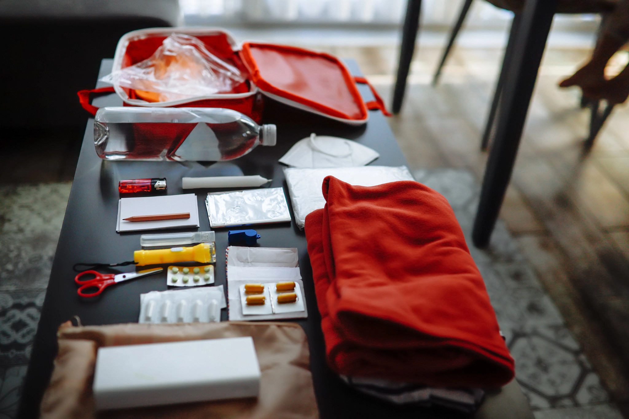 Preparation for natural disasters concept with go bag materials displayed on a table.
