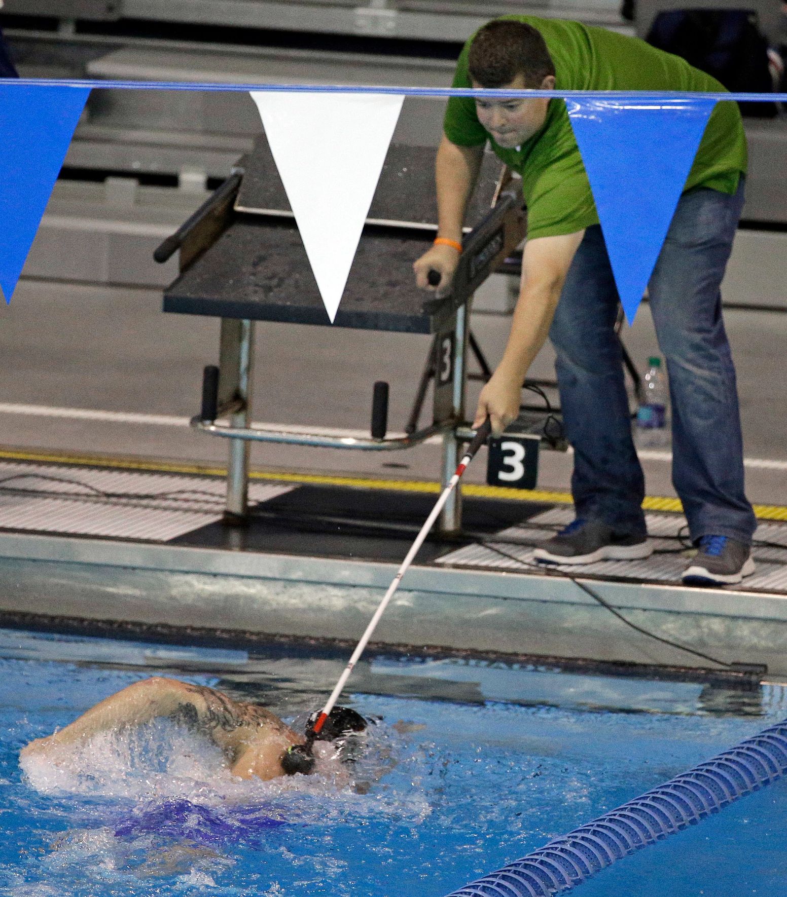 Brad Snyder a volunteer uses a pole to tap a swimmer on the back
