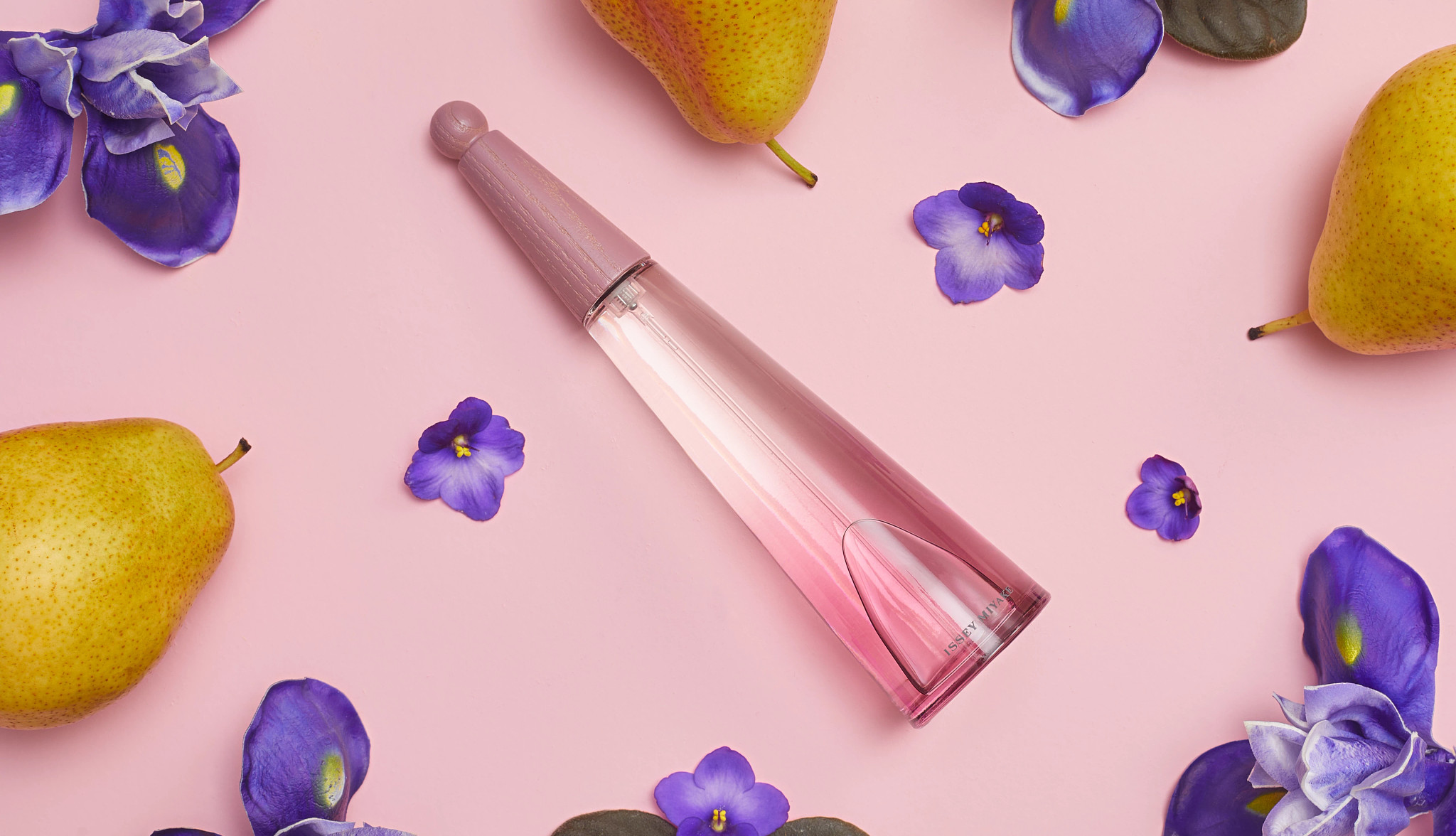 Bottle of Issey Miyake L’Eau d’Issey Solar Violet surrounded by pears and violets 