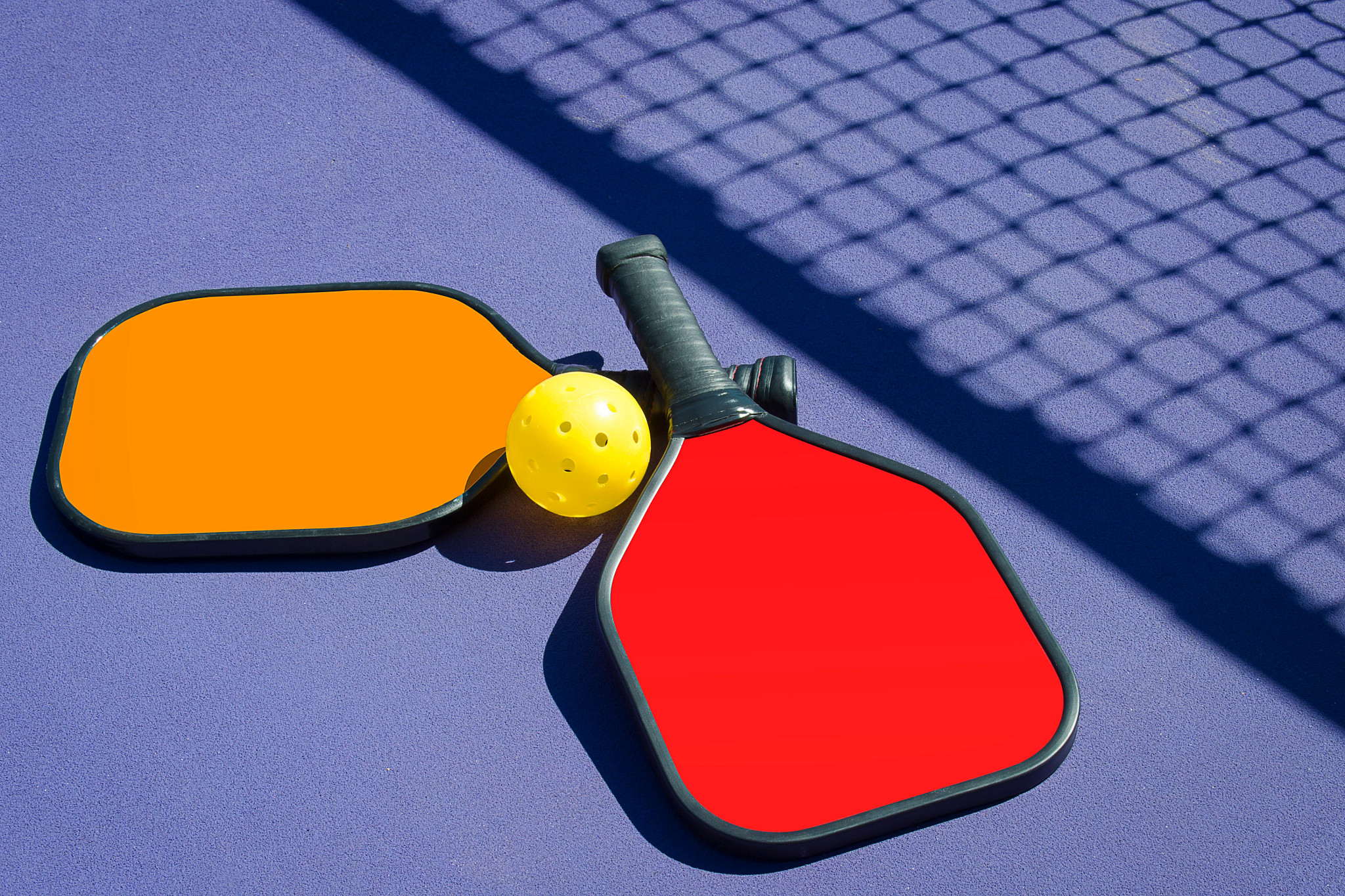 Pickleball - Two Paddles and A Ball in Net Shadow