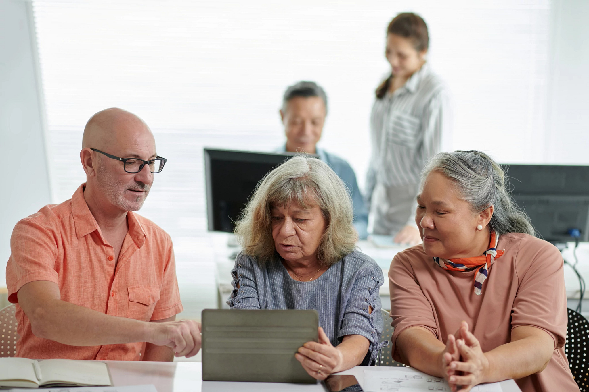 Man helping classmates to install application on tablet computer