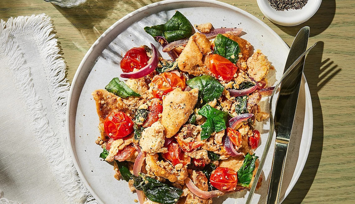 A close-up view of scrambled eggs with spinach, feta and pita on a plate