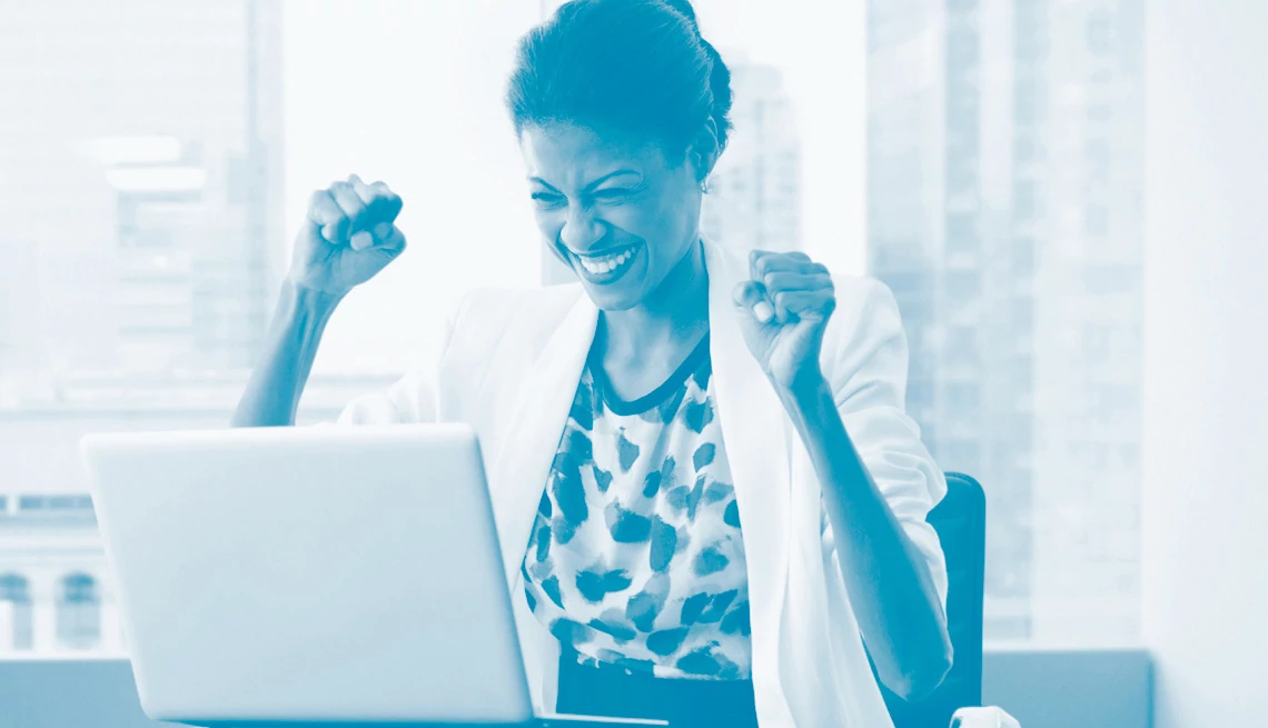 Mujer feliz sonriendo en la mesa de su oficina frente a una laptop Mujer feliz sonriendo en la mesa de su oficina frente a una laptop