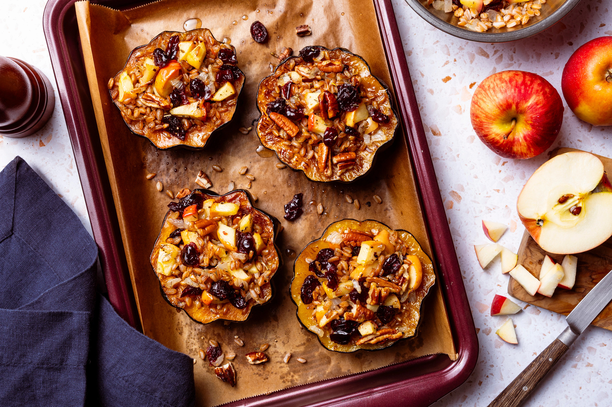 Stuffed acorn squash with apples, pecans and dried cranberries on a baking tray.