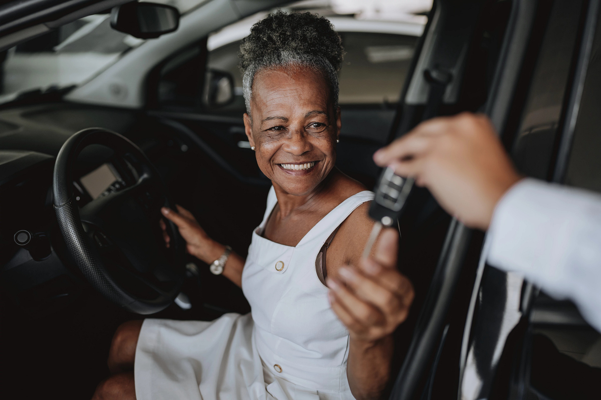 a woman sitting in a car and being handed keys
