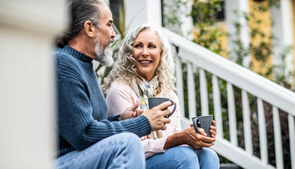 Couple drinking coffee while sitting on the front steps of their home