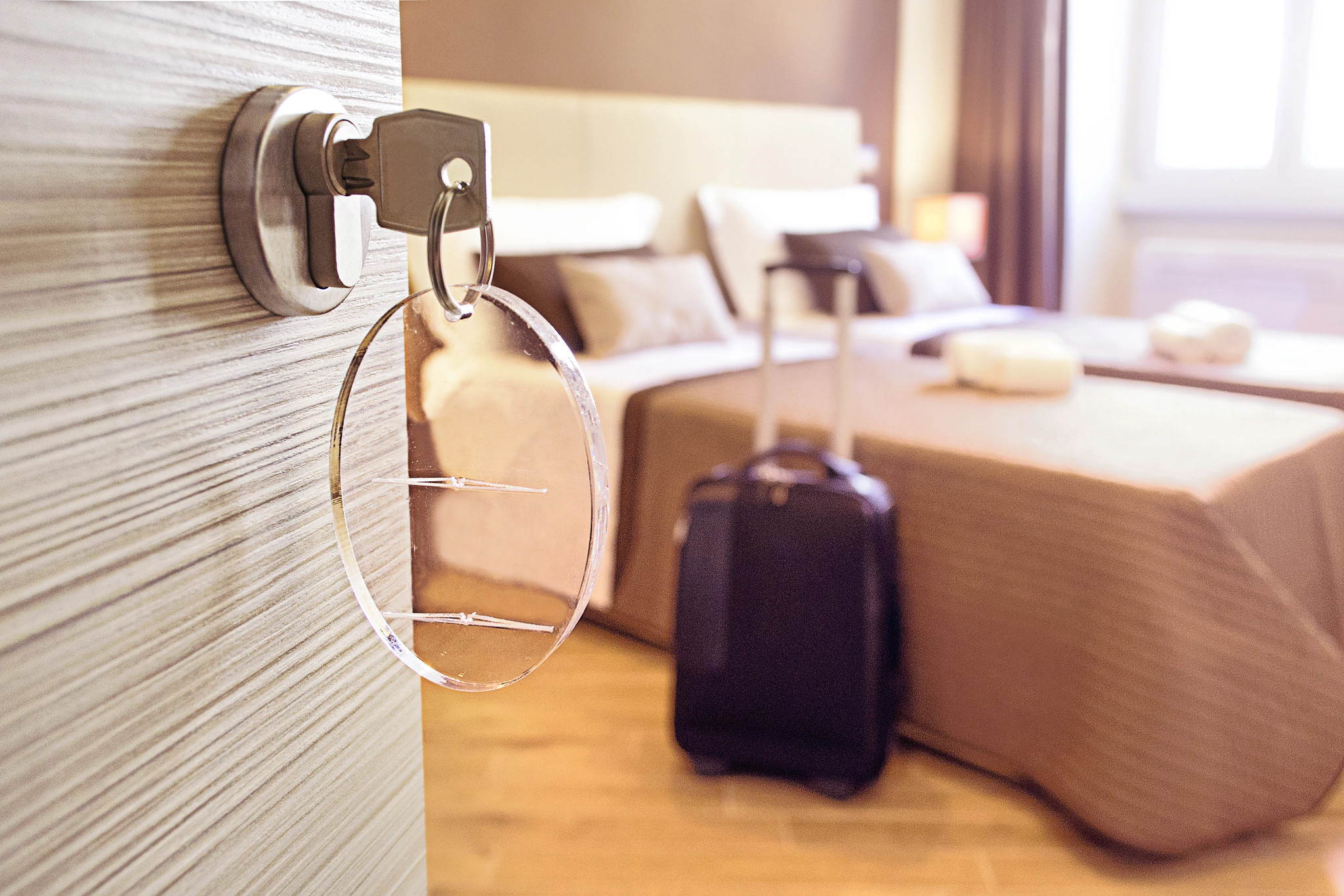 an open hotel room door showing bed and luggage in the background