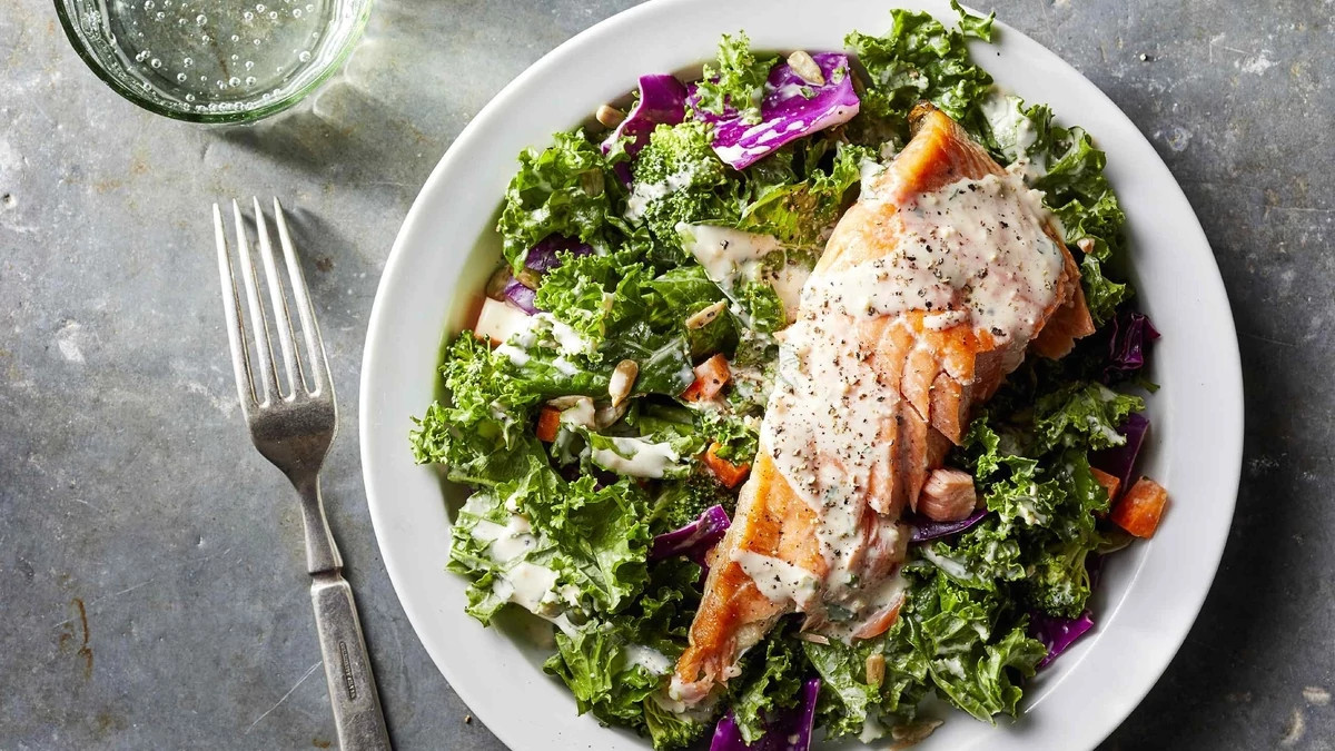 A close-up view of superfood chopped salad with salmon and creamy garlic dressing on a plate