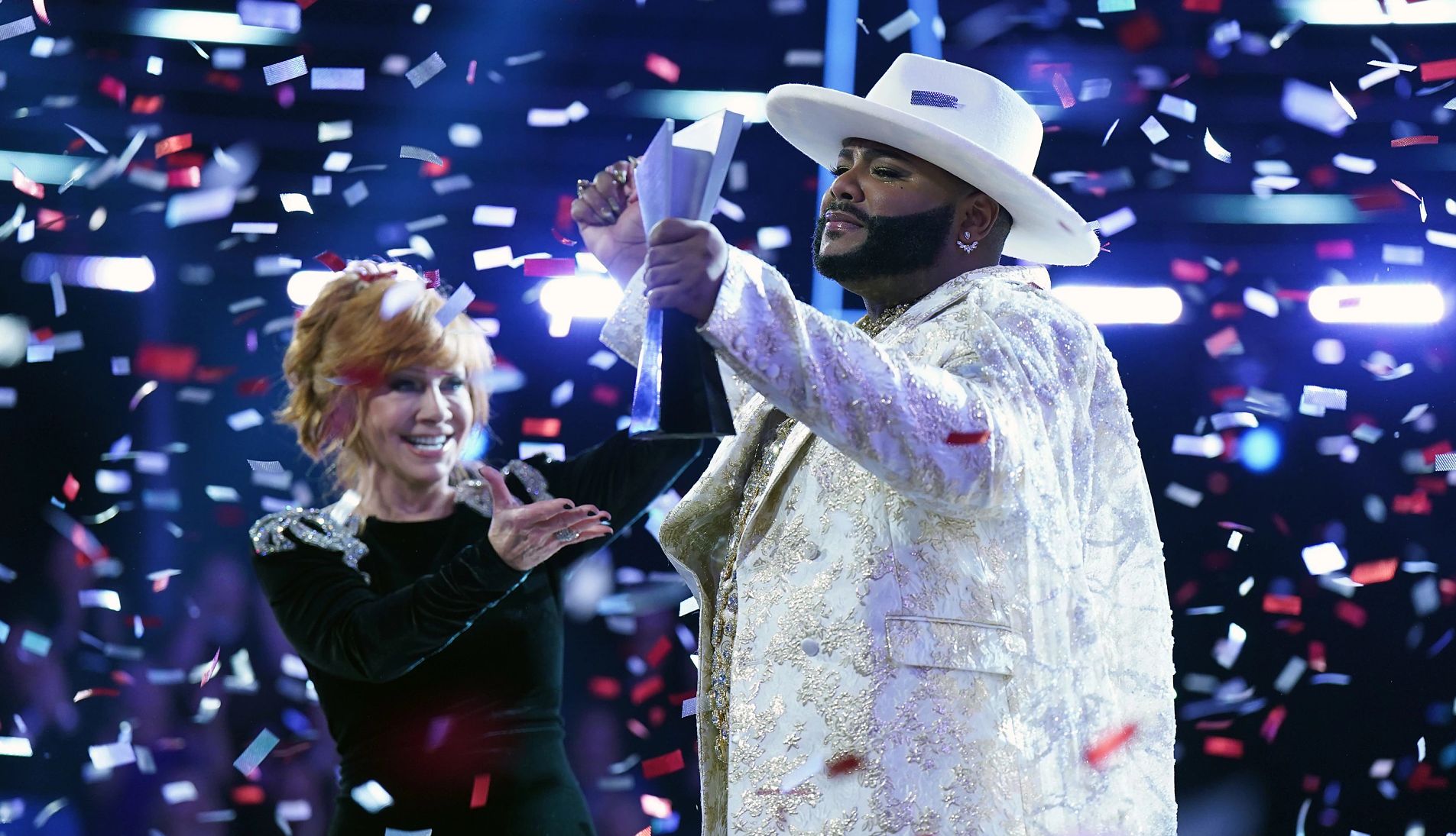 Asher HaVon holds up his trophy alongside Reba McEntire as confetti falls to the ground on the Season 25 finale of The Voice