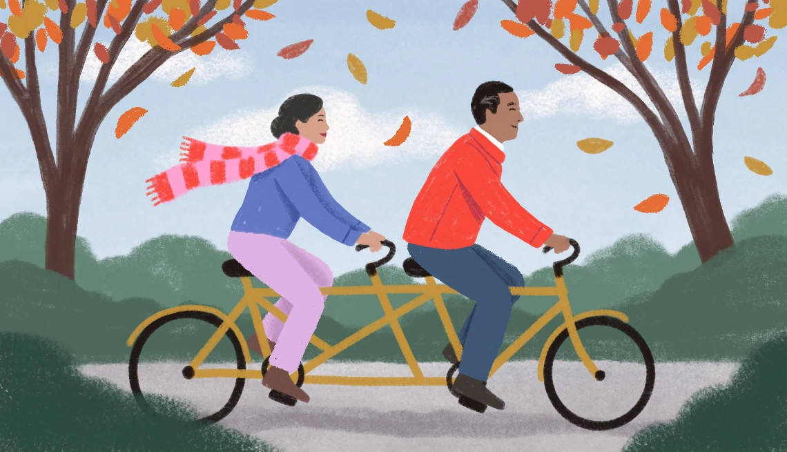 a couple rides a tandem bicycle through fall foliage