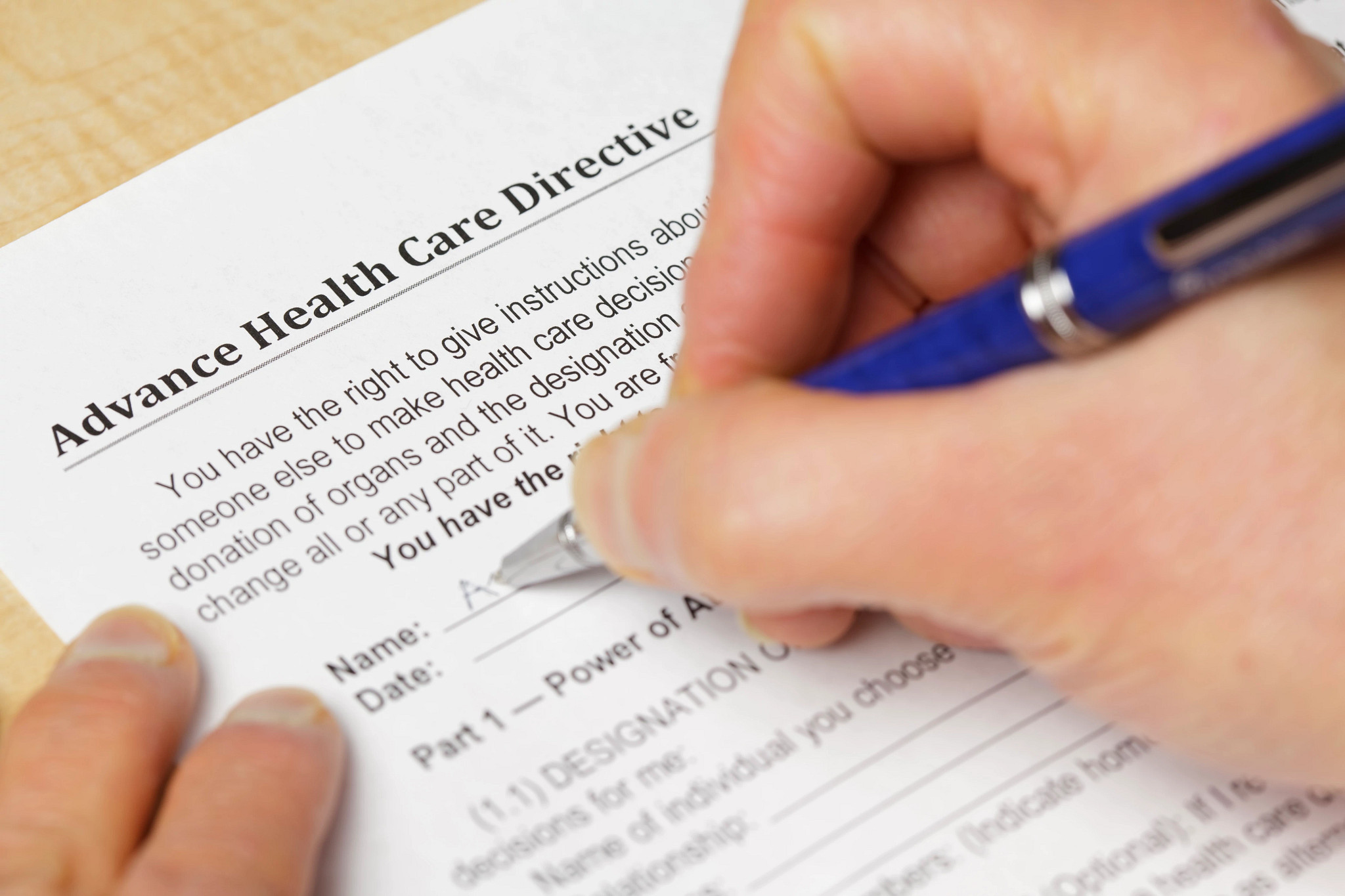 A person filling out a form titled Advance Health Care Directive and a pen. 