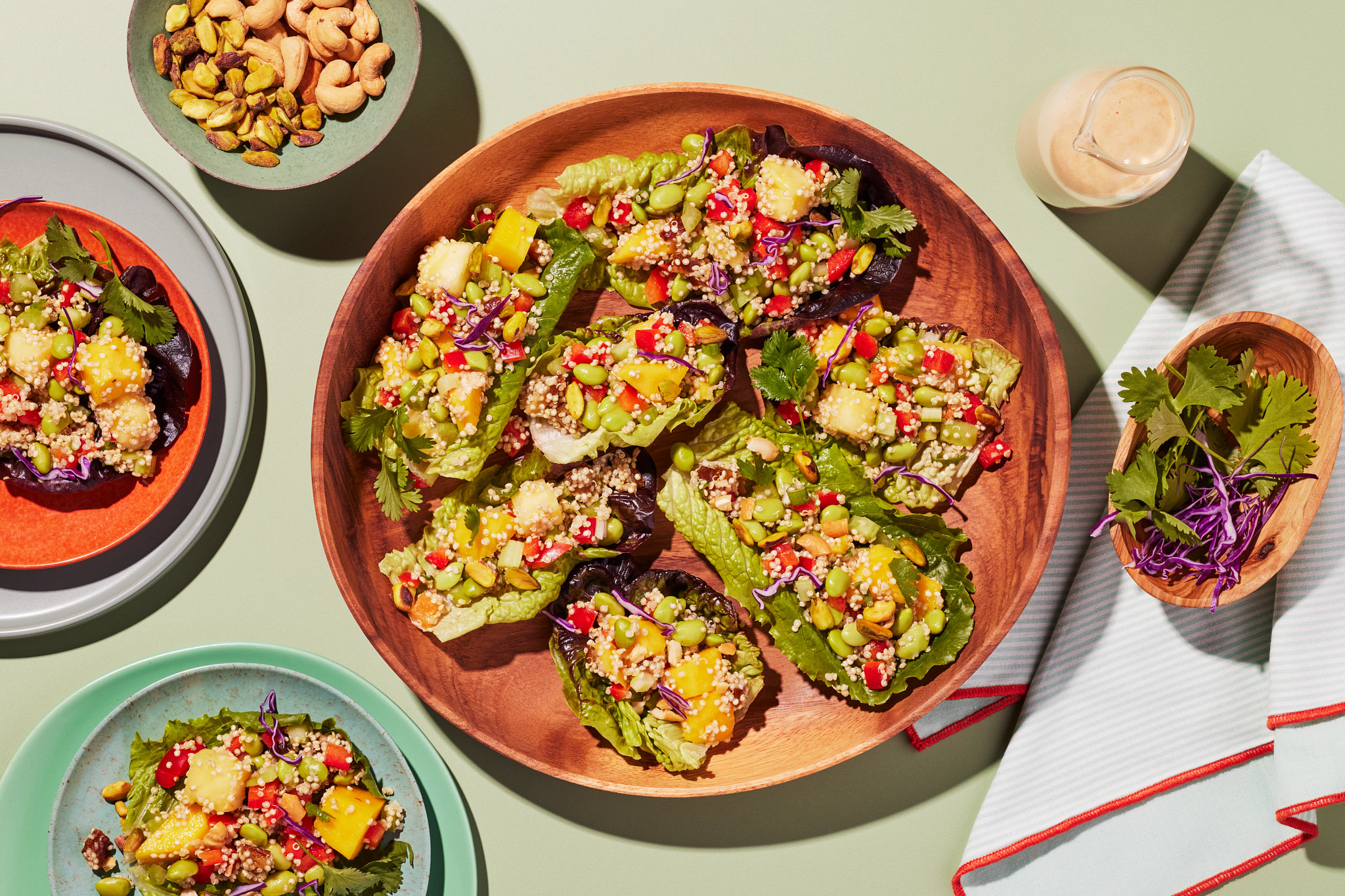 Colorful plant-based lettuce wraps filled with quinoa, vegetables, and nuts arranged in a wooden bowl