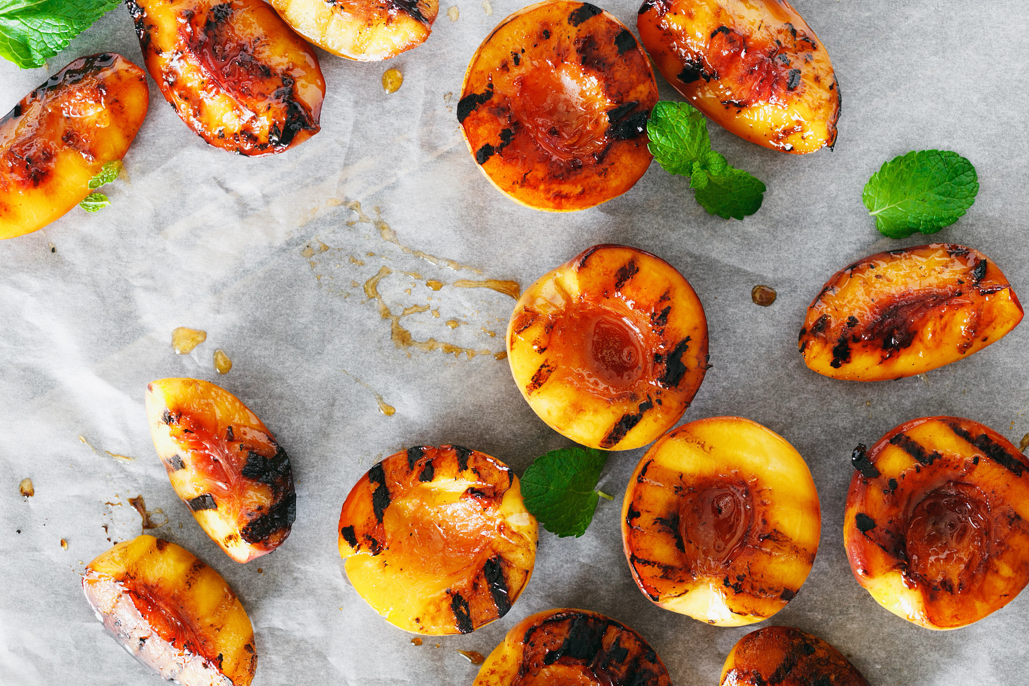 Miso-glazed grilled peaches are pictured atop parchment paper.