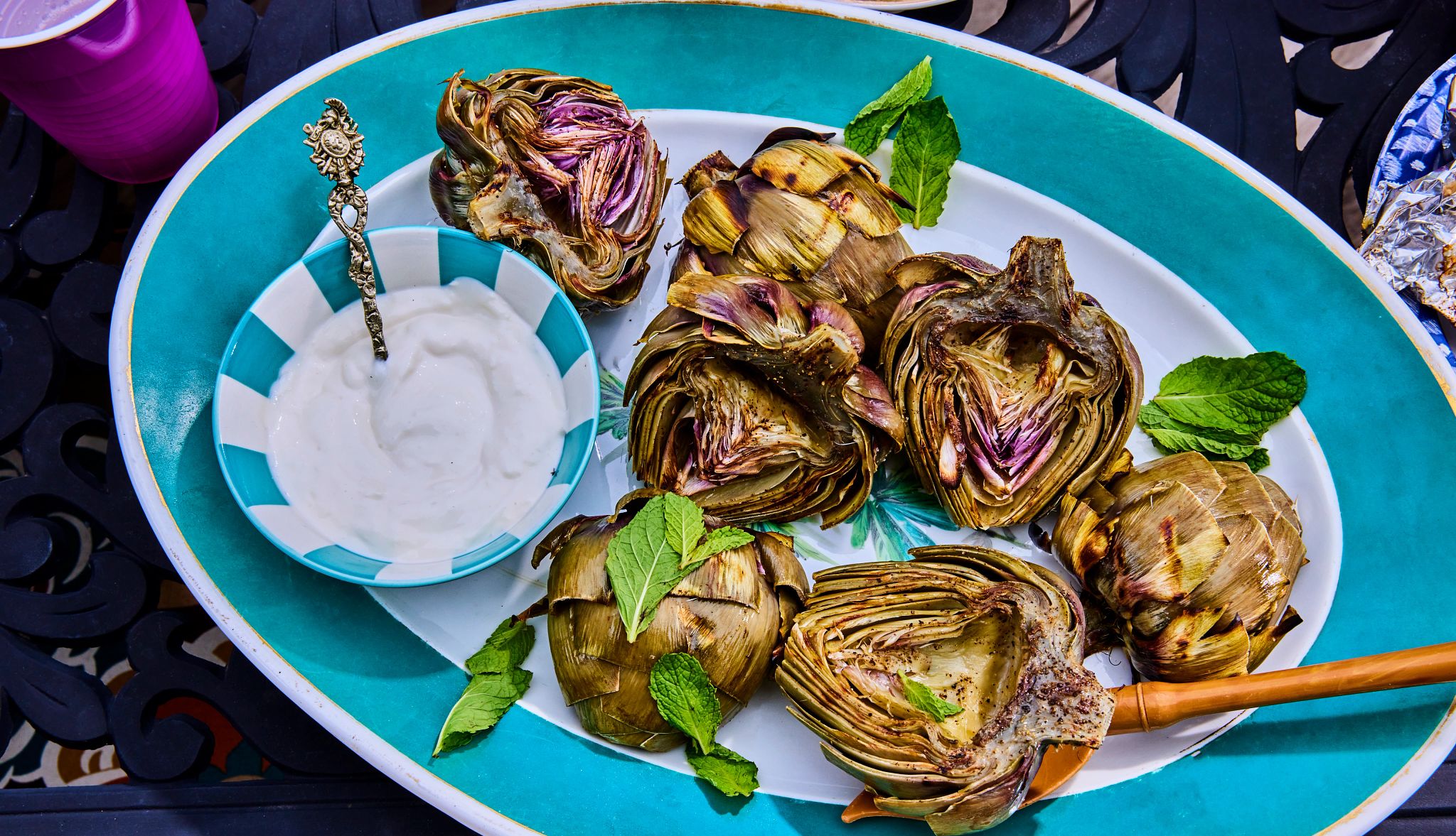 Grilled Artichokes With Lemon Aioli Recipe Artichokes on dish with small bowl of lemon aioli