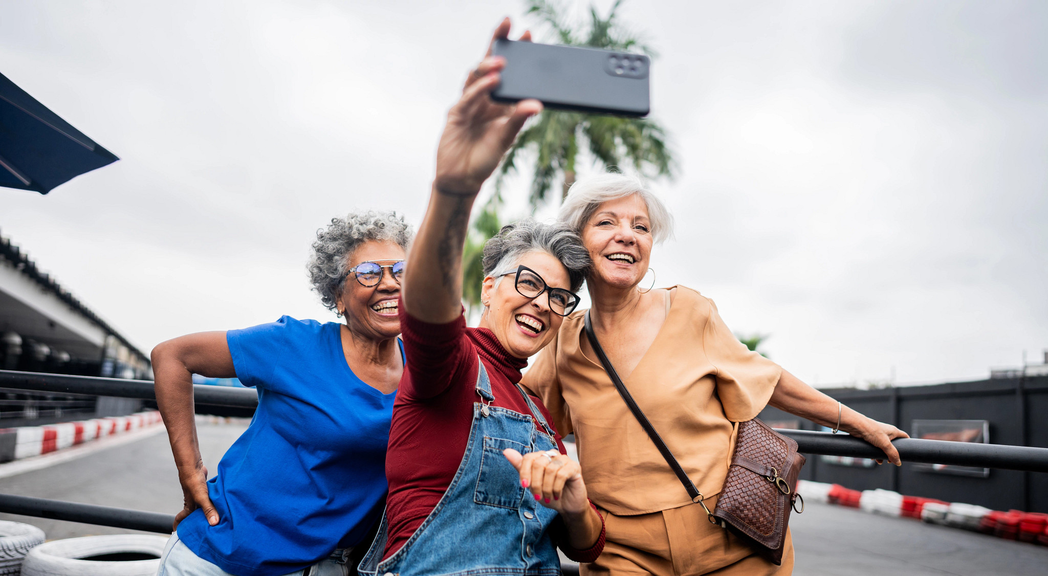 Three women taking a selfie near a race track