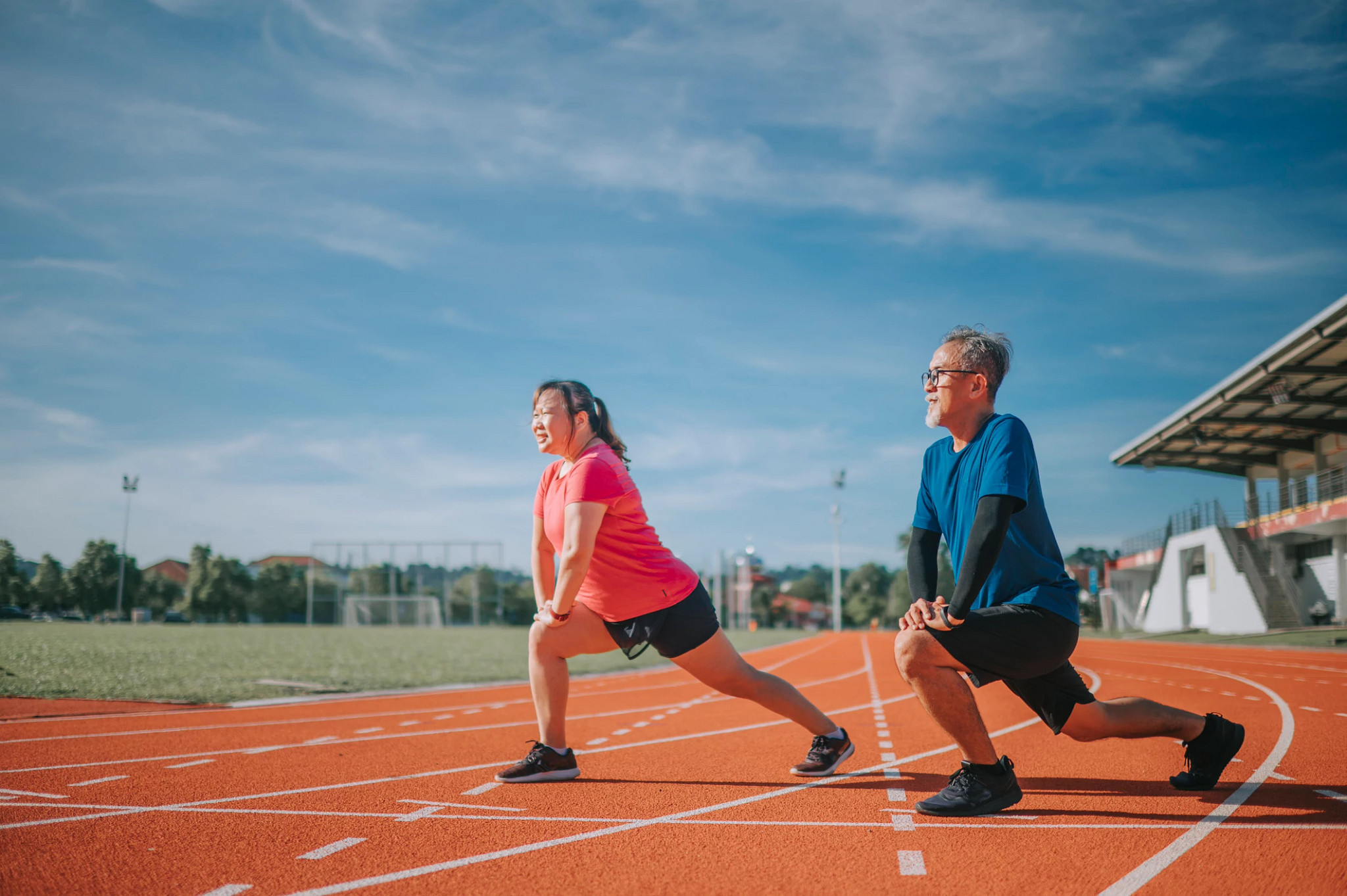 Asian Chinese senior couple warm up exercise before the running at track and field stadium in the morning