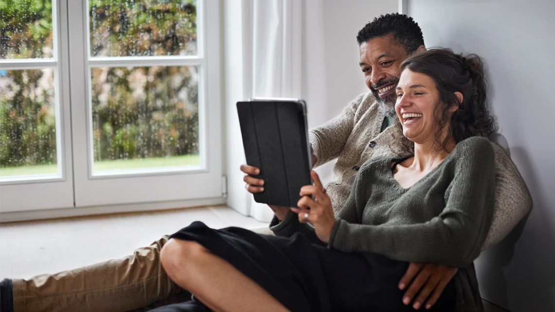 Man and woman laughing at tablet