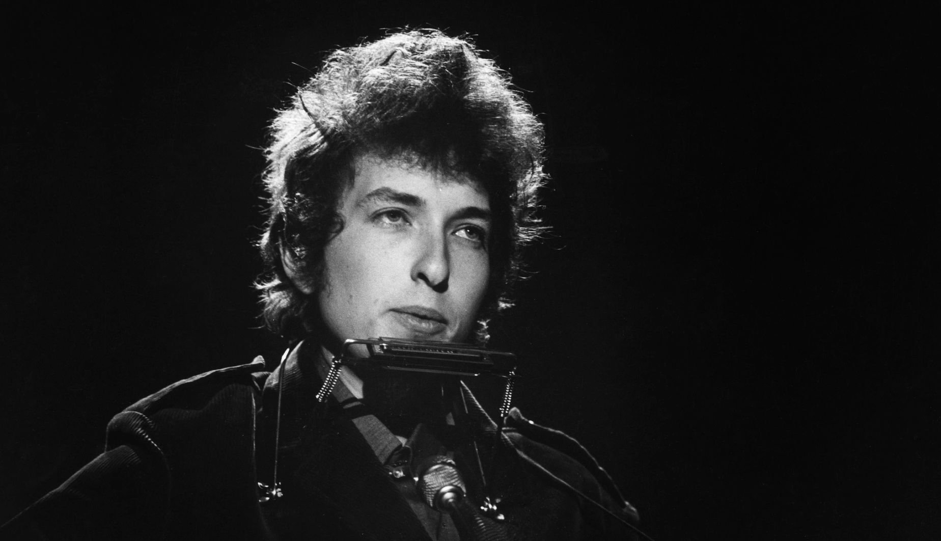 Portrait of musician Bob Dylan A black and white portrait of Bob Dylan in front of a microphone with a harmonica