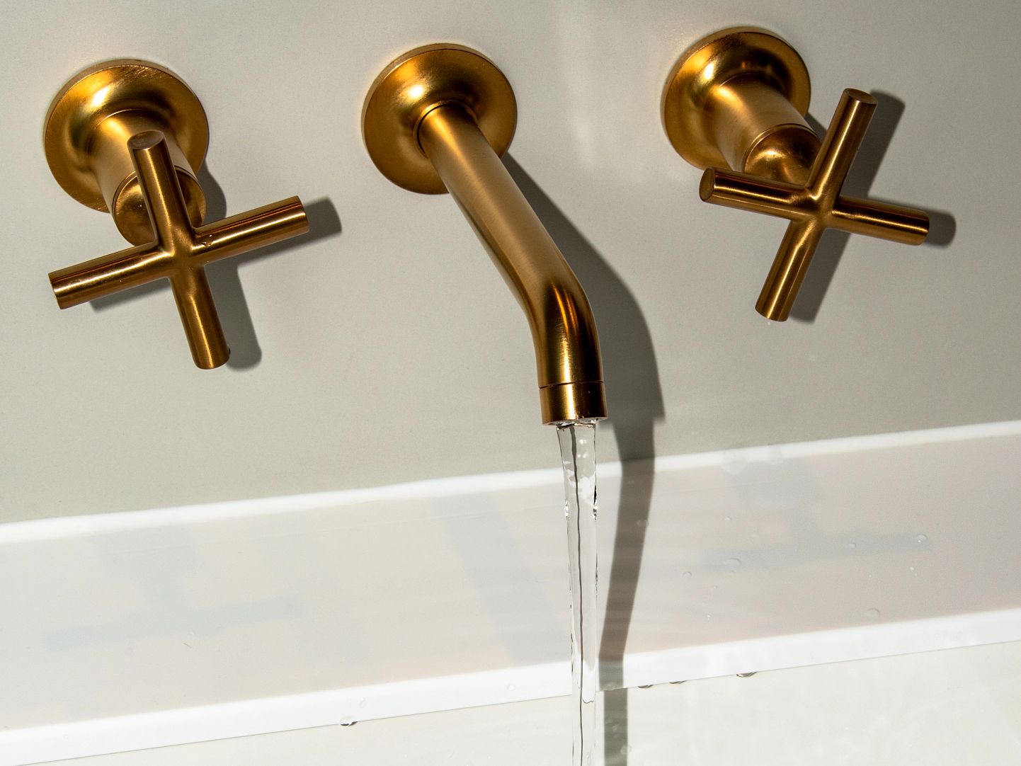 Hot and Cold Water flwoing from a Gold Coloured Stainless Steel Faucet
