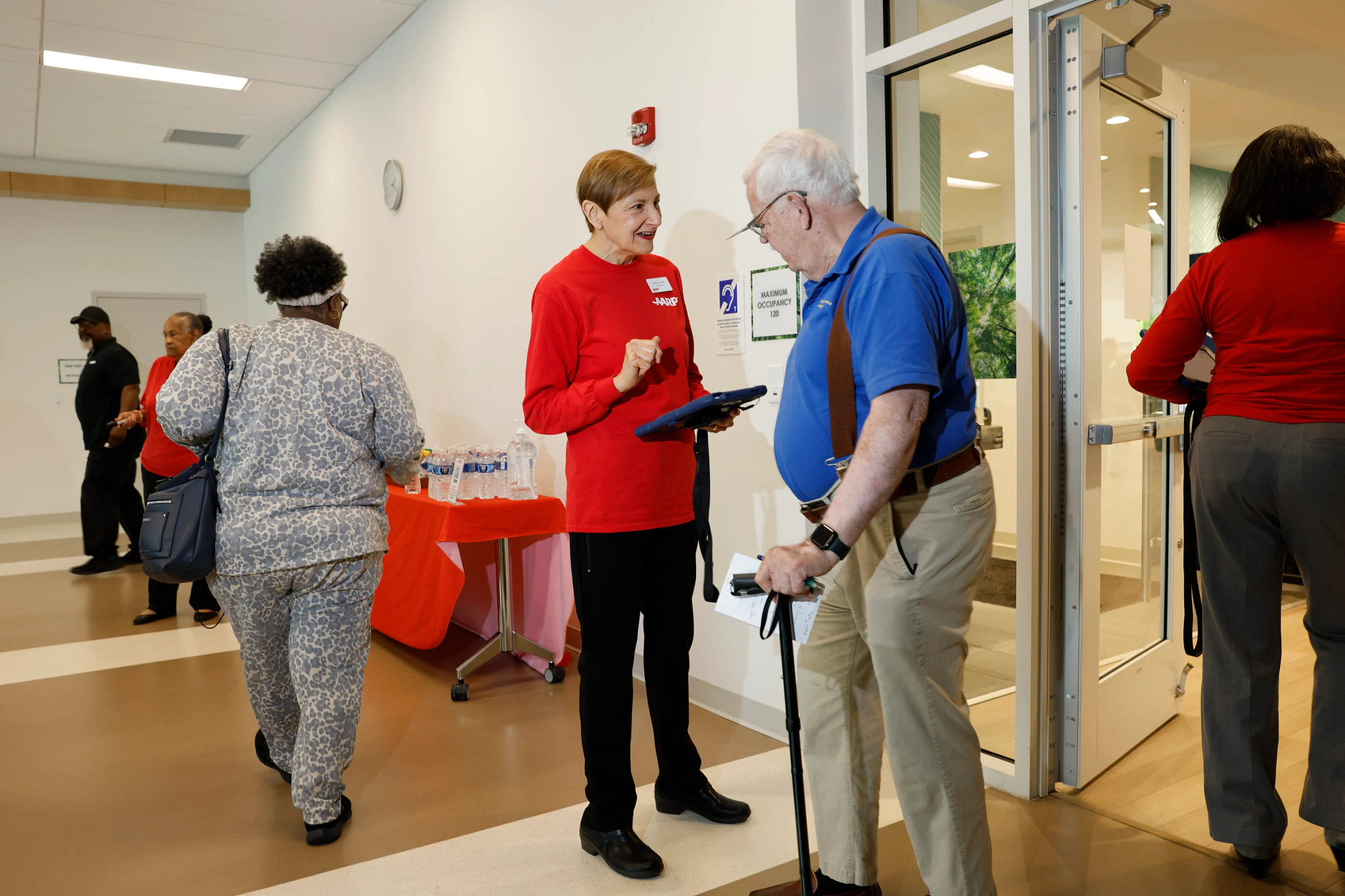 a woman in a red AARP shirt helping a man