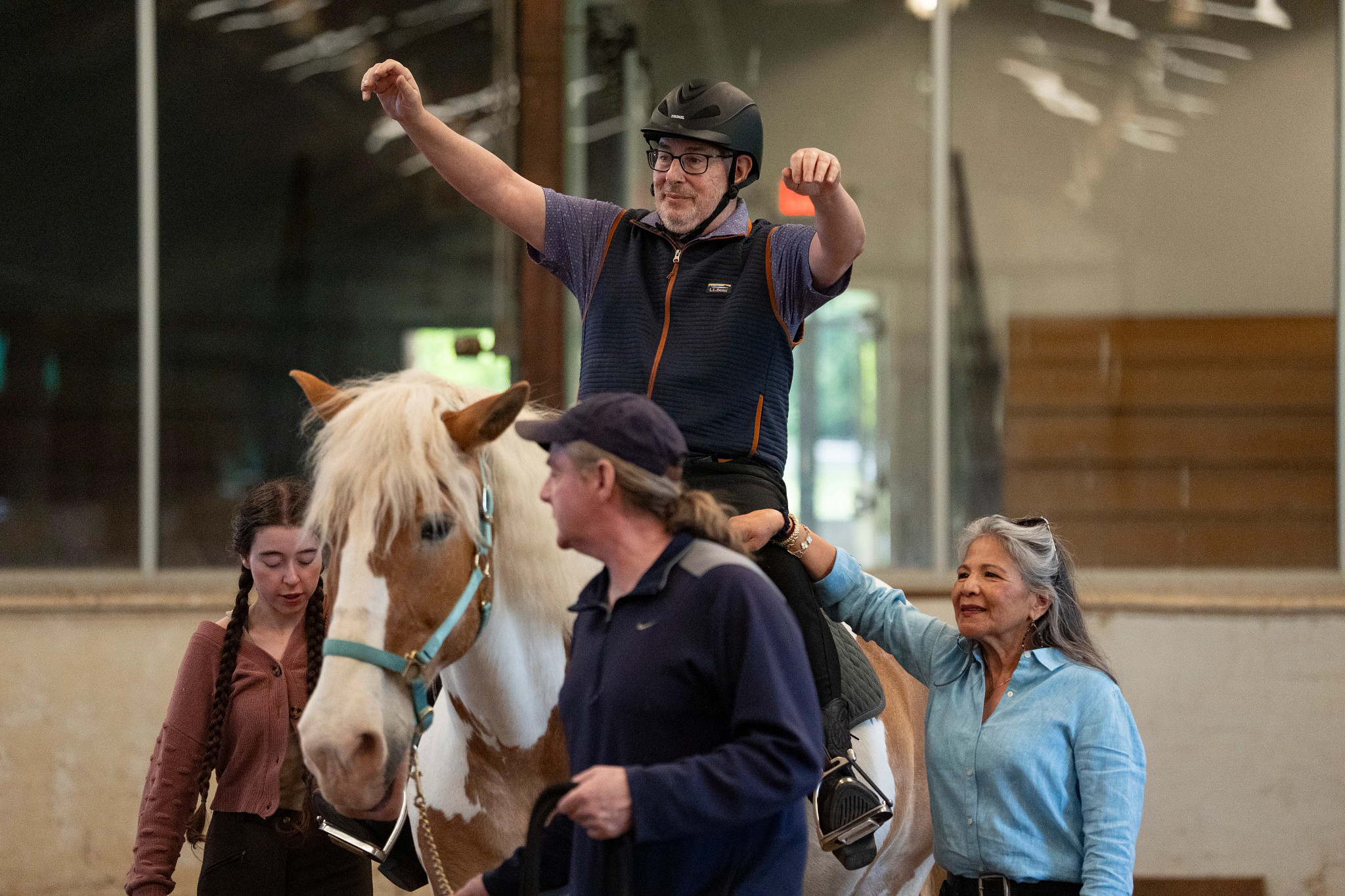 people helping another person ride a horse