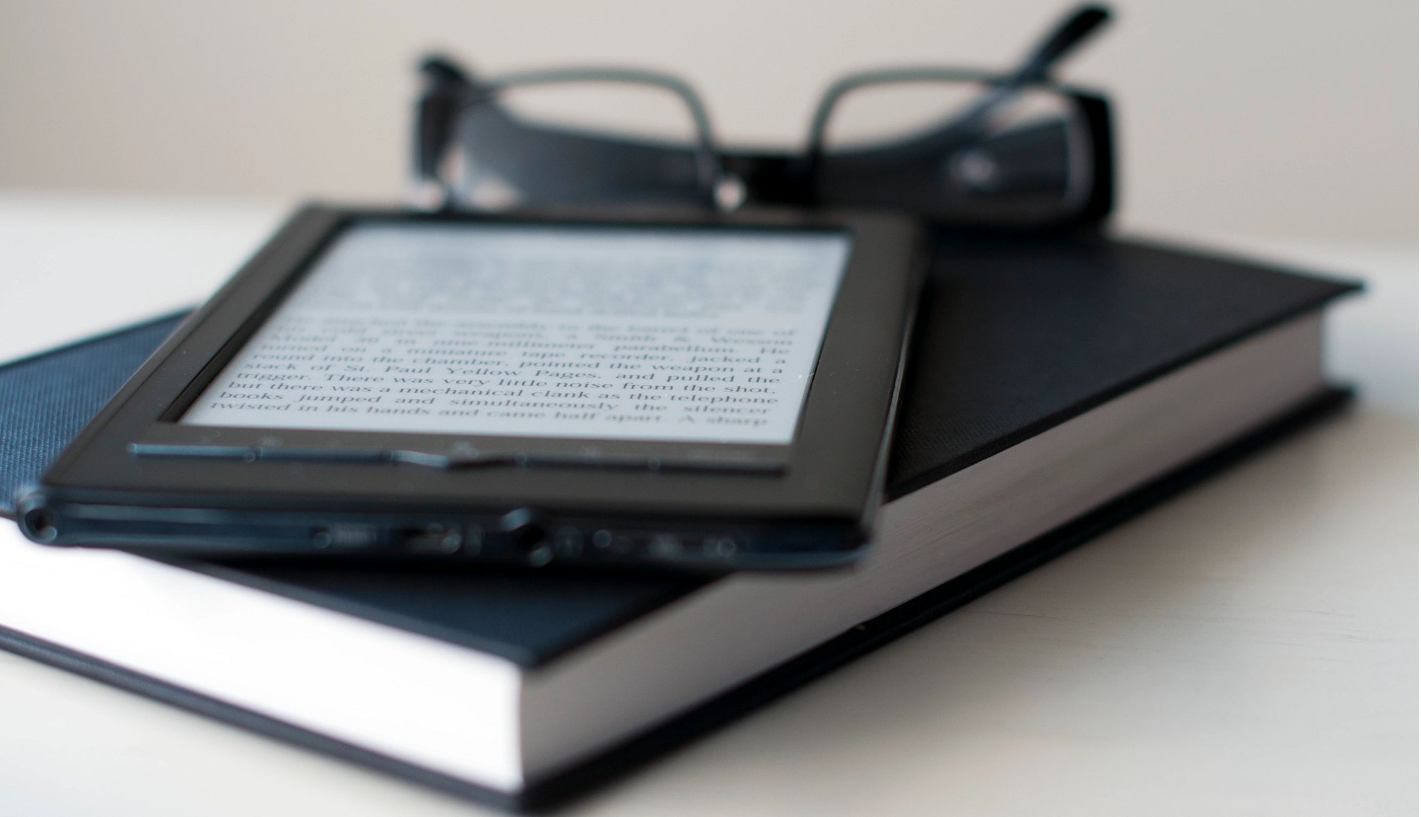 E-Reader and book with reading glasses. E-Reader and book with reading glasses.