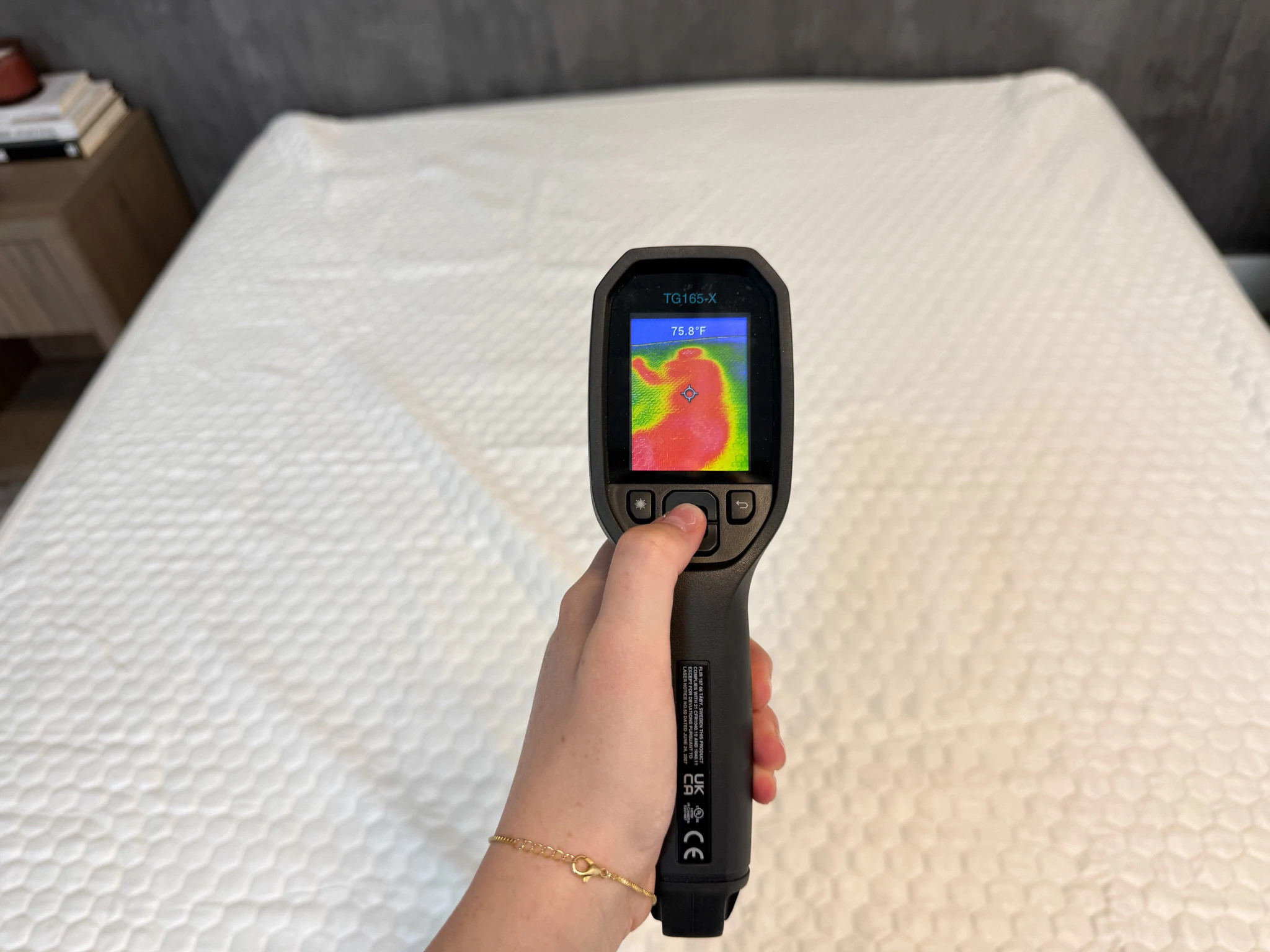 A thermal gun being held up to the Nolah GlacioTex Cooling Mattress Protector after testing.