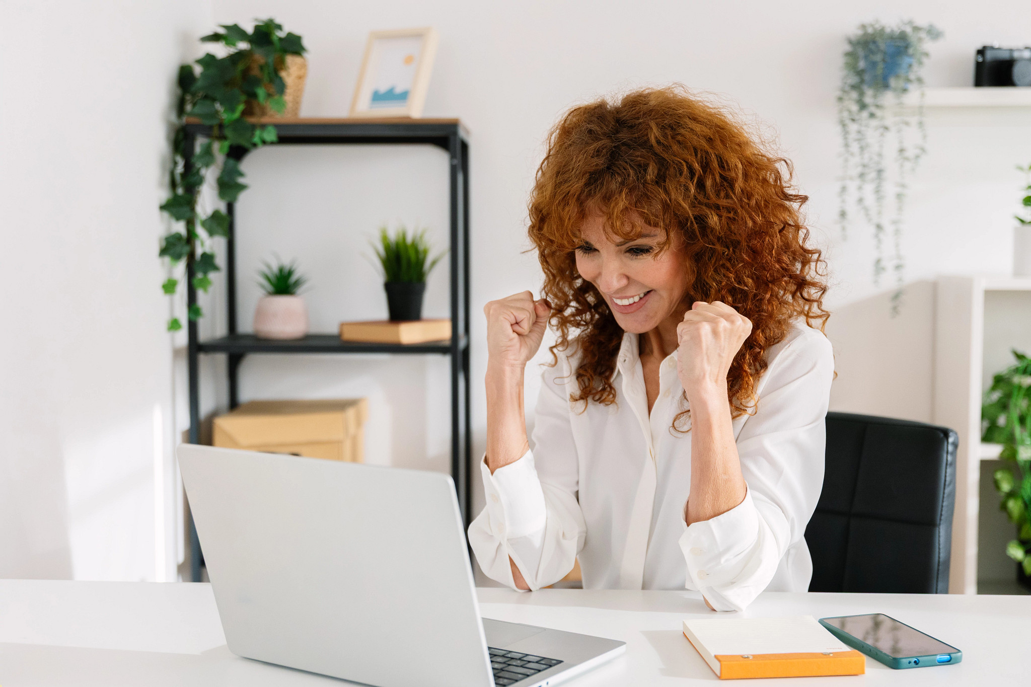 Mid adult businesswoman celebrating good news on laptop. Happy professional reacting to business success. Success and business concept.