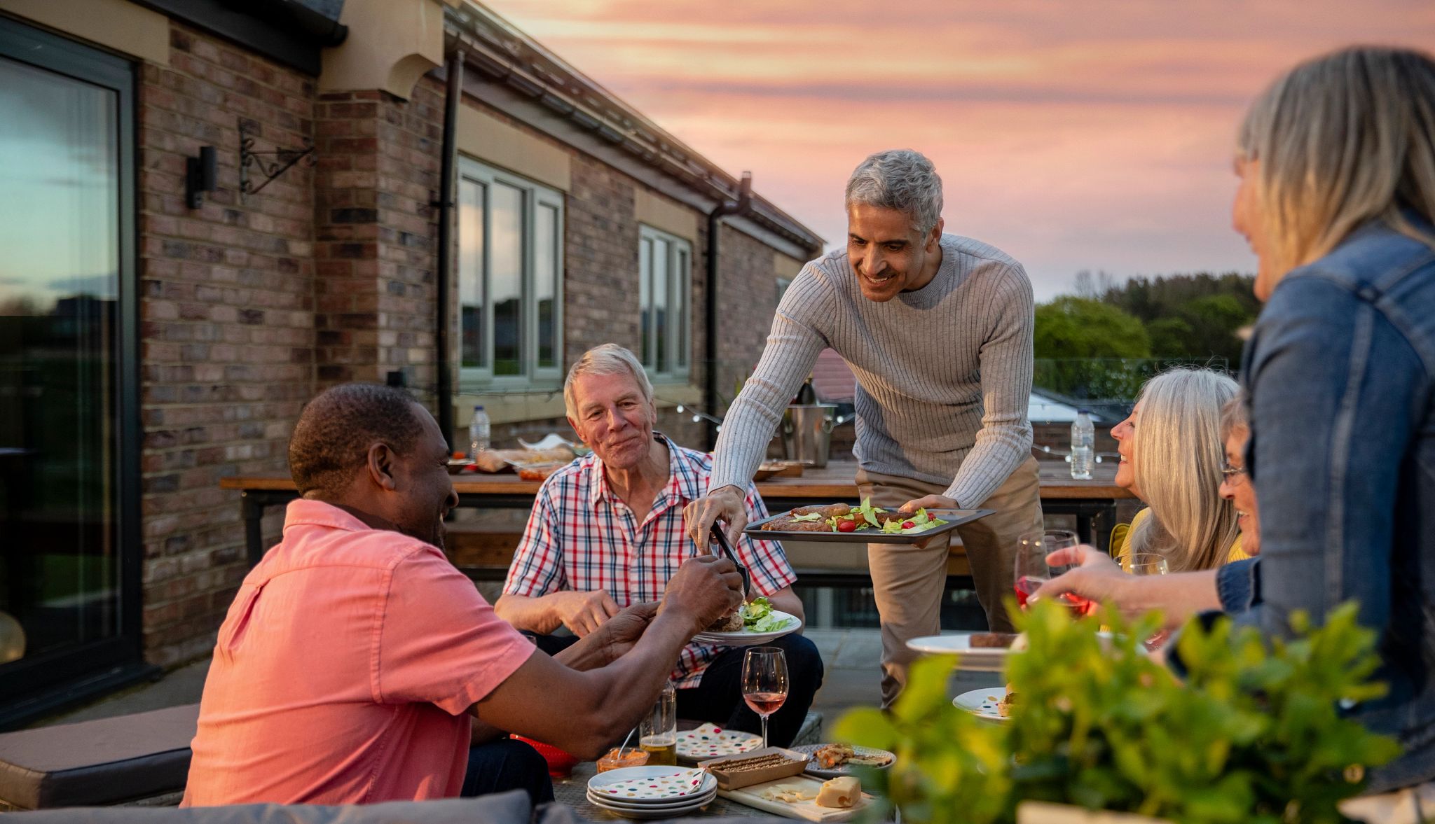 Group of senior friends/couples sitting outside together eating/drinking/having a bbq. Group of senior friends/couples sitting outside together eating/drinking/having a bbq.
