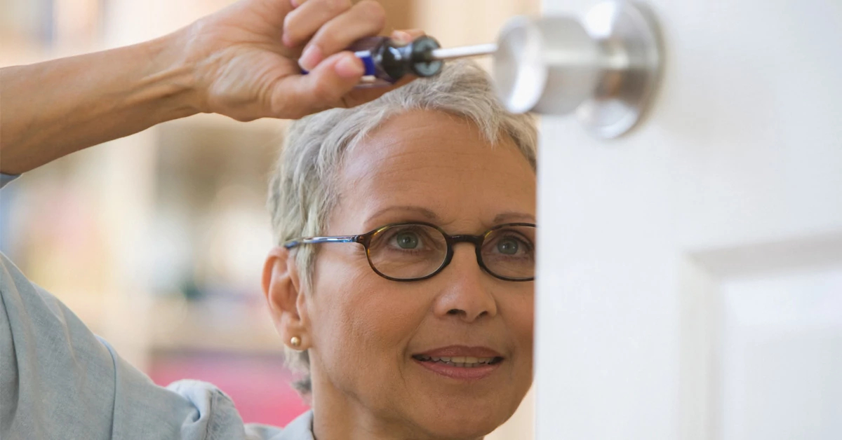 Woman working on door with screwdriver in hand