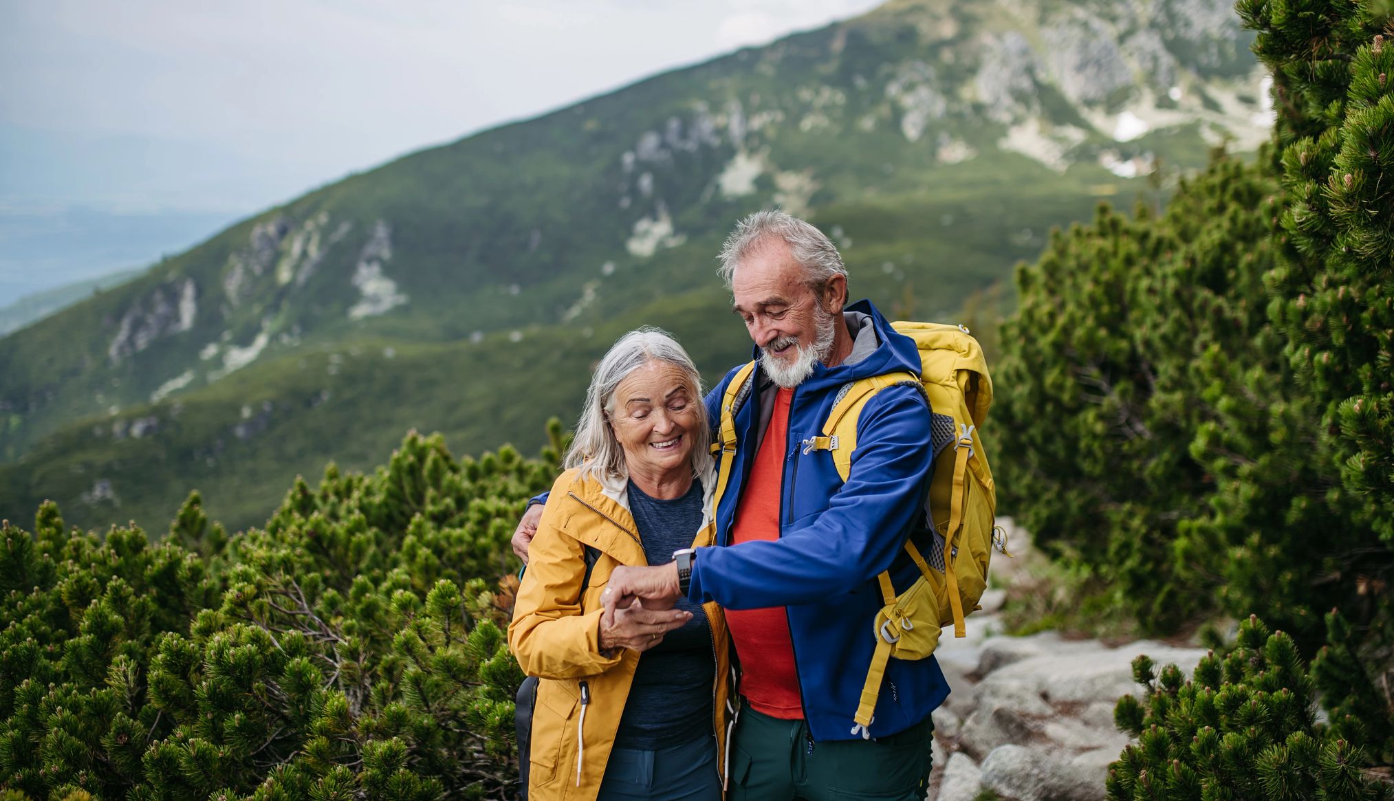 Senior woman checking vitals on smartwatch during hike.