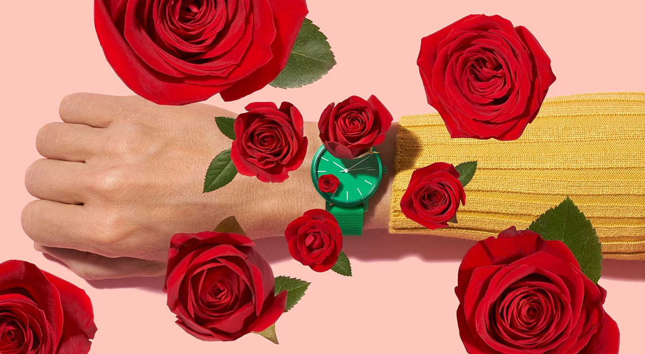 Woman's arm with a green watch and roses popping out of the frame