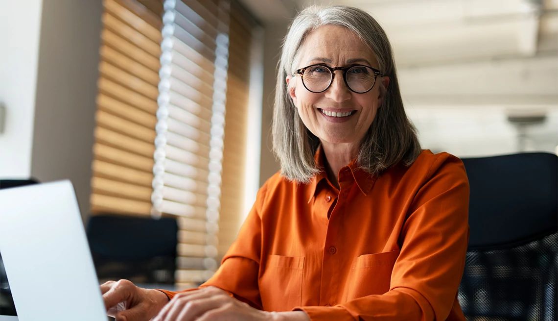 Woman wearing business clothes and glasses working on a laptop
