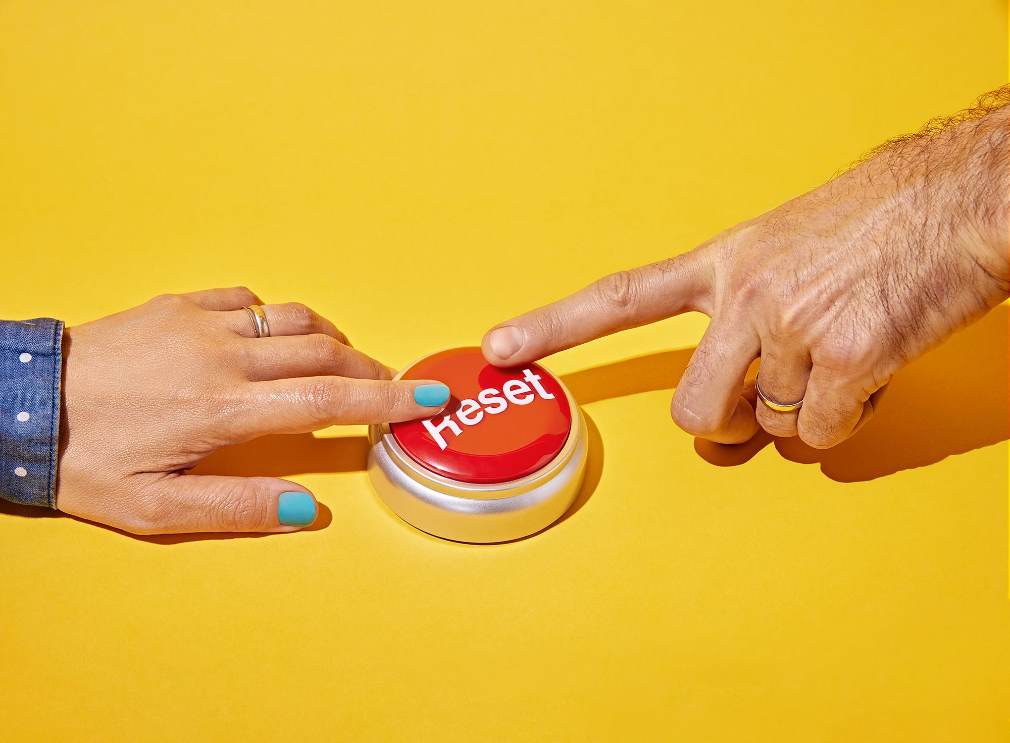 Female and male hand pressing a reset button