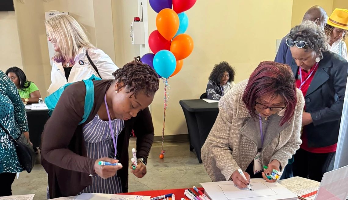 AARP’s Staying Sharp program provided access to valuable brain health resources at the Brain Health Action booth Two women participants making signs at the AARP booth at the 2025 Alter Dementia Summit