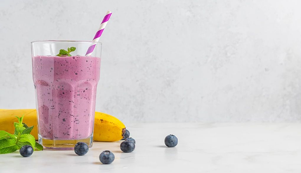 Smoothies can provide a lot of nutrition A blueberry and banana smoothie with a banana and blueberries beside it
