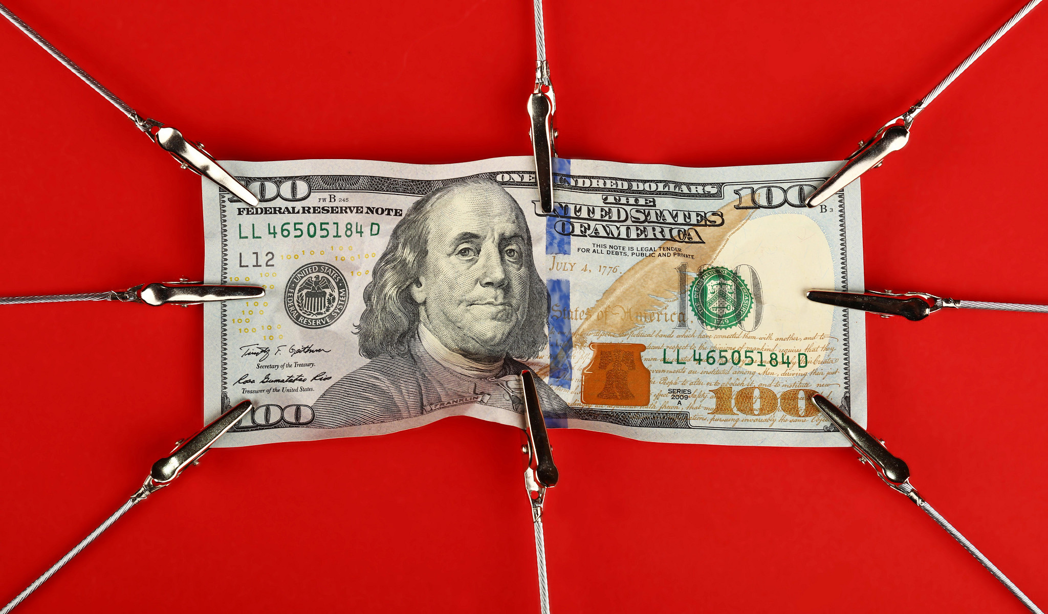 eight clips grasp a hundred dollar bill on a red background