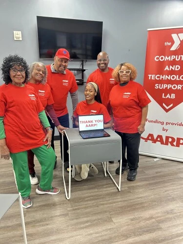 computer and technology support lab volunteers posing next to a thank you a a r p sign
