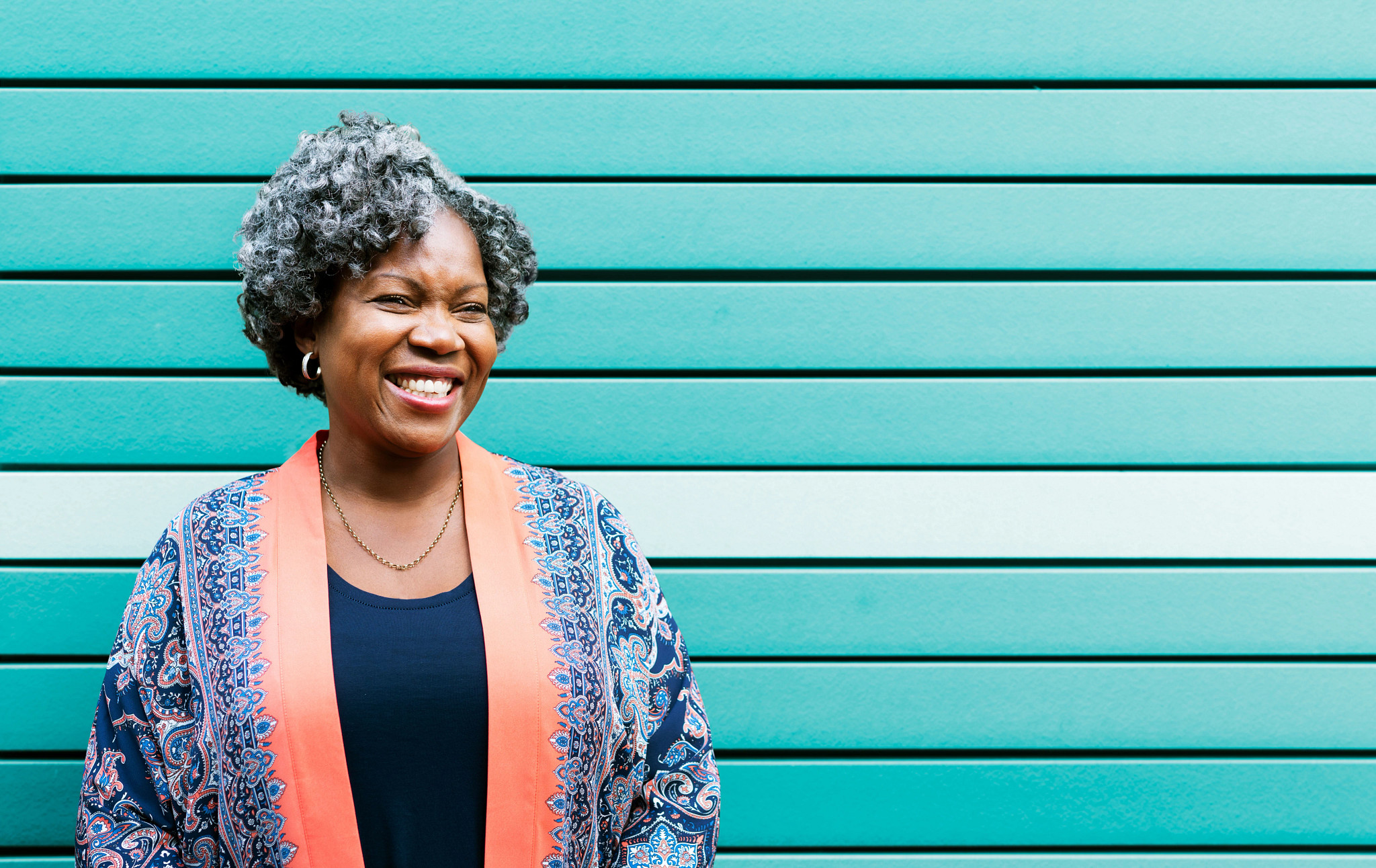 Woman smiling in front of a turquoise wall