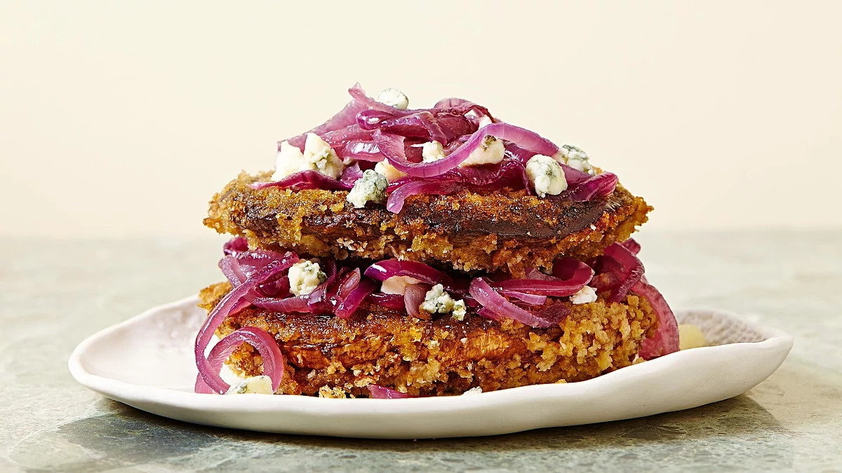 A close-up view of crispy portobello with caramelized onion and blue cheese on a plate