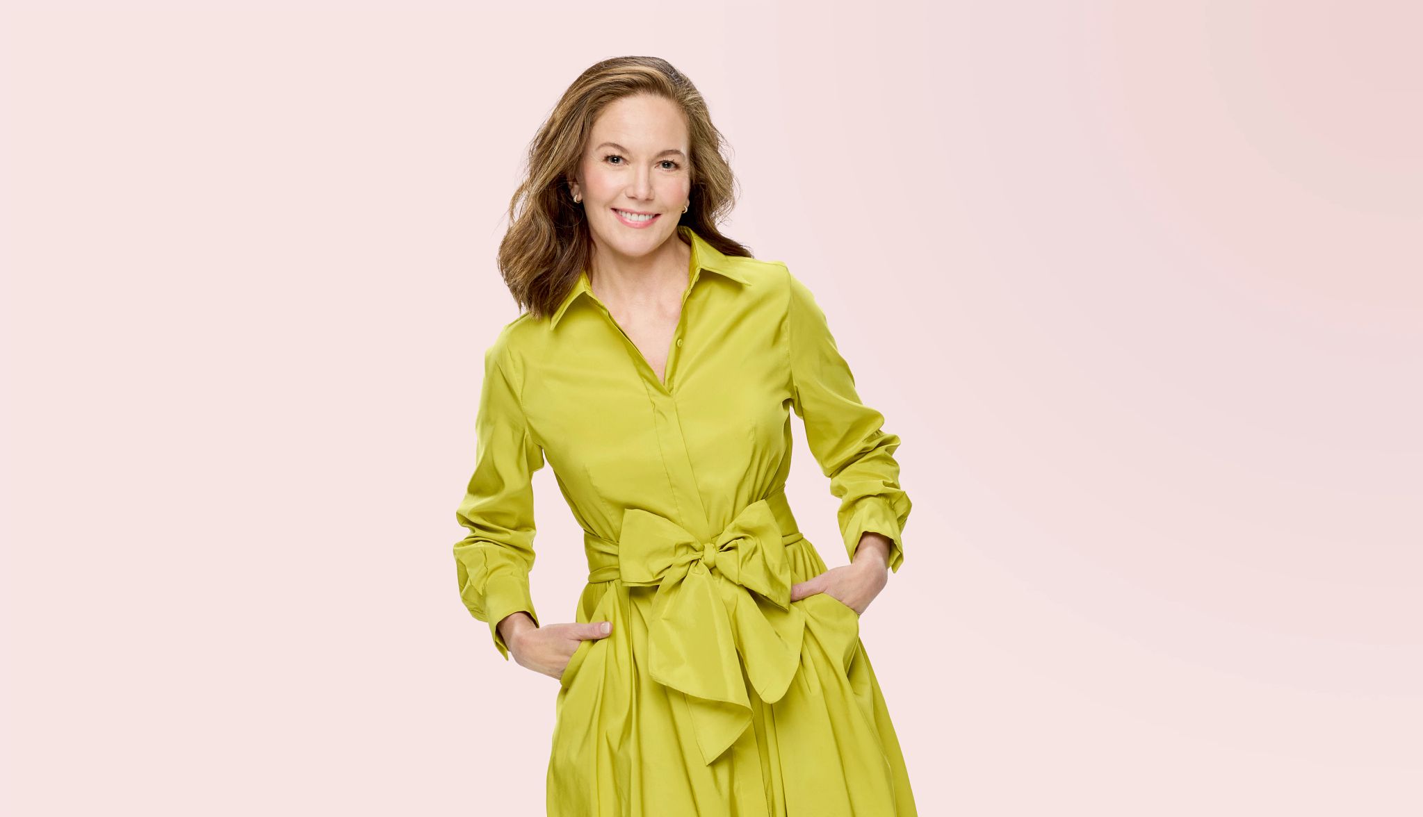 Diane Lane in long yellow coat against nude background
