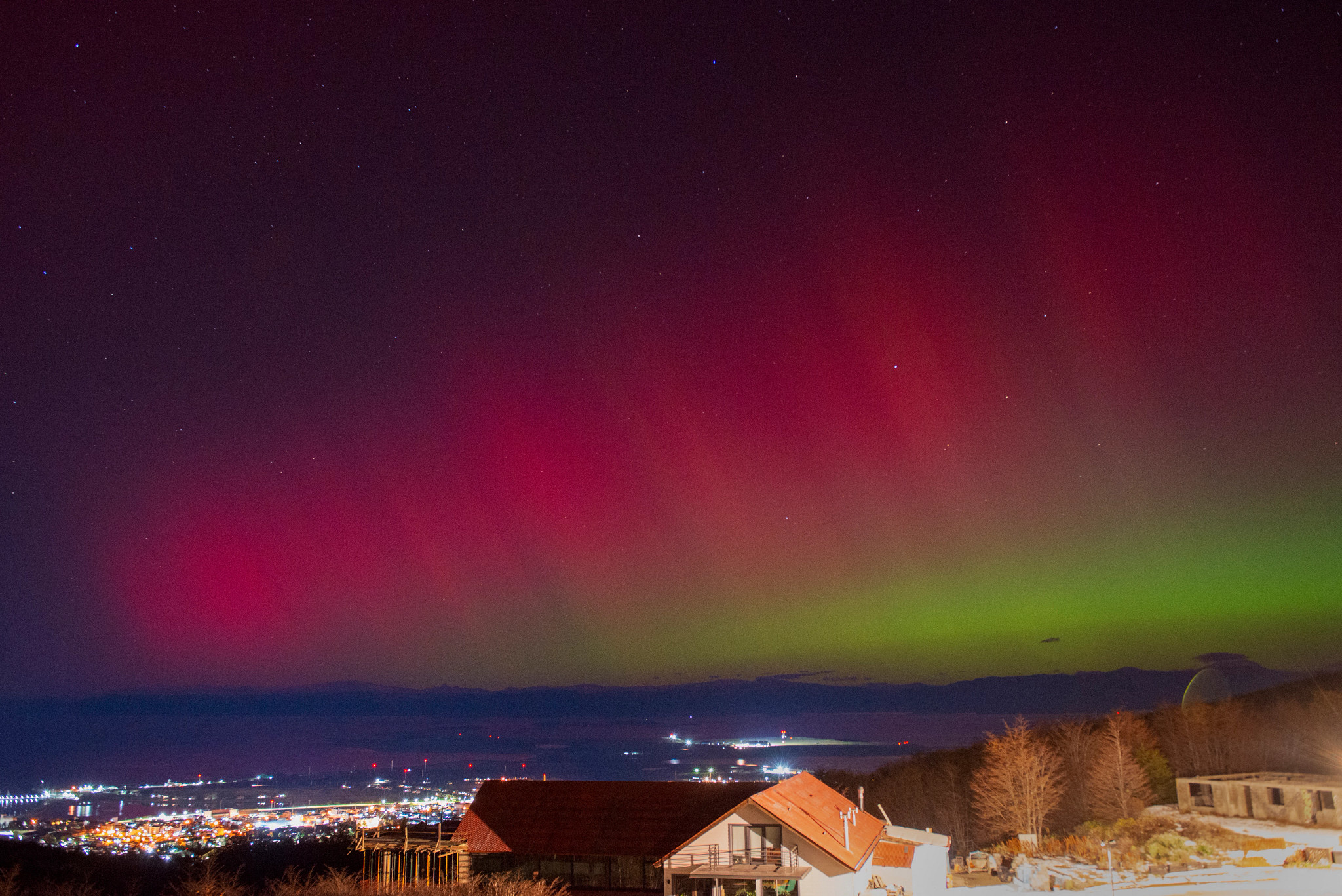 a homes and a cityscape with the southern lights in the background