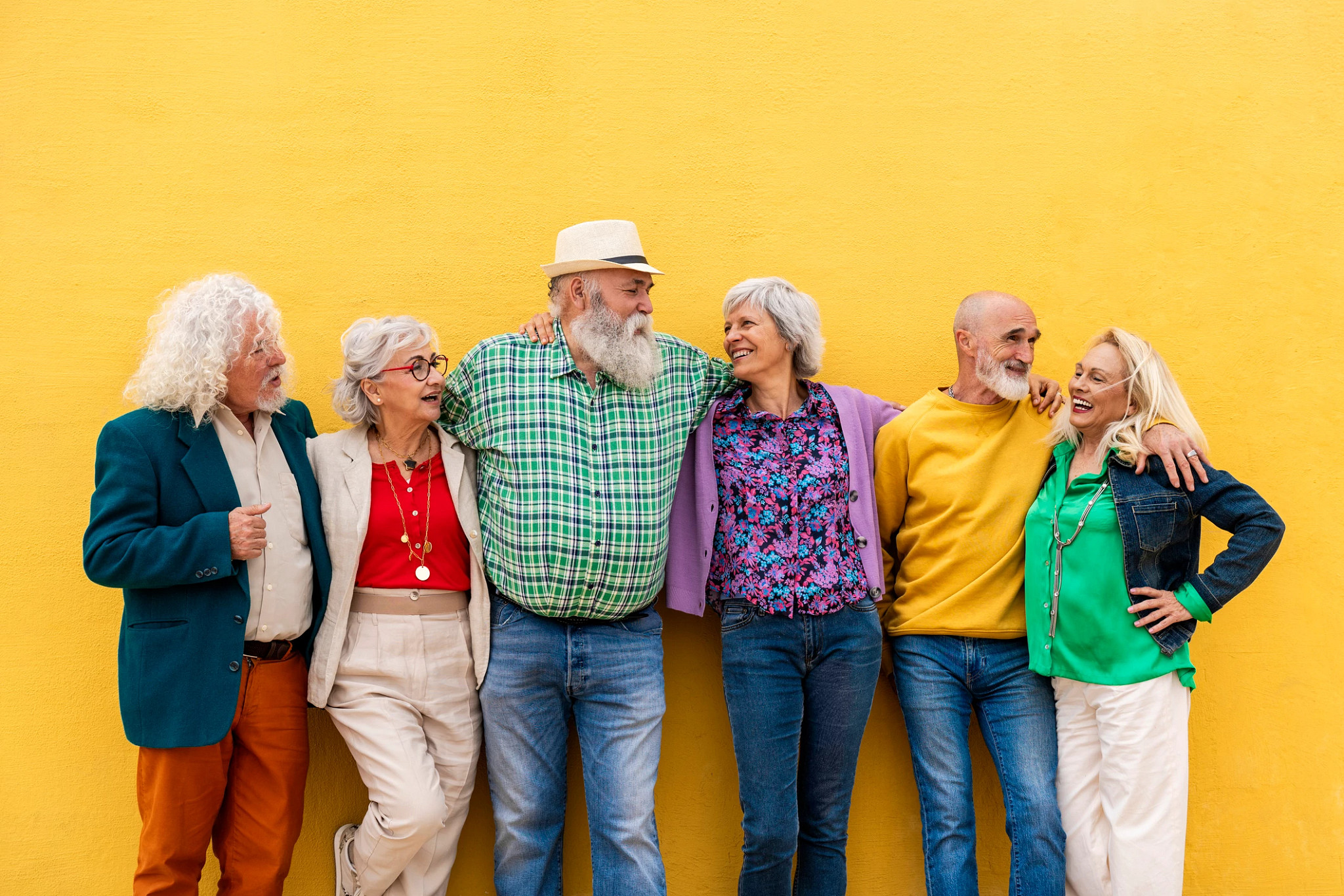 a group of people standing before a yellow wall